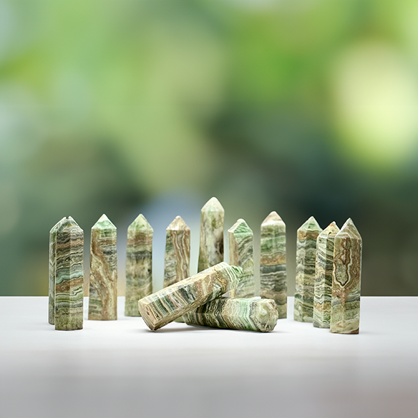 Set of Green Calcite crystal towers arrayed on a white surface against a blurred green background