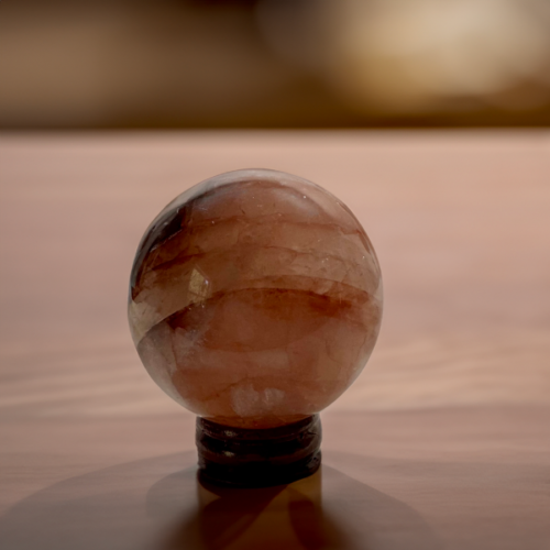 Polished Fire Quartz sphere displaying rich pink and white bands on a wooden stand