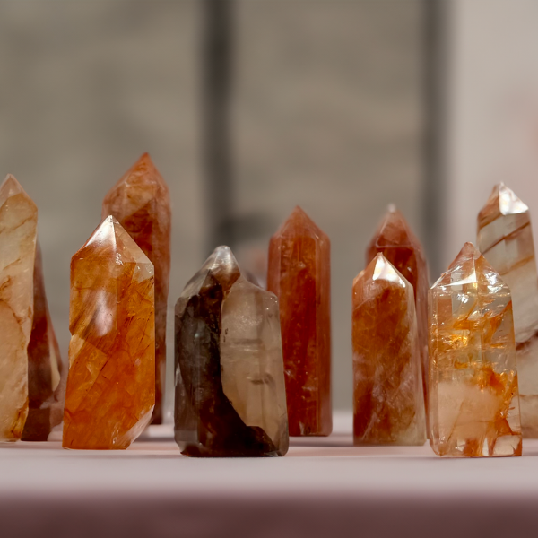 Array of Fire Quartz crystal towers with rich orange and white striations on a light pink surface